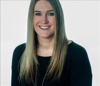 Blonde woman in SERVPRO uniform posing for a picture on a white background