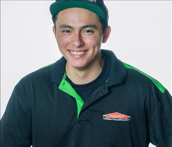 Man in a hat and SERVPRO uniform posing for a picture on a white background