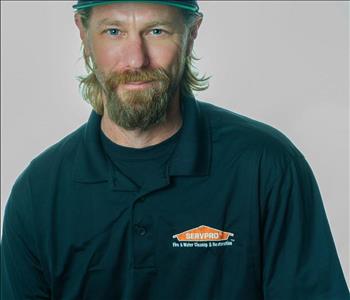 Man in a hat and SERVPRO uniform posing for a picture on a white background