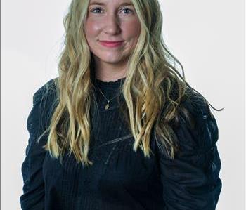 Blonde woman in SERVPRO uniform posing for a picture on a white background