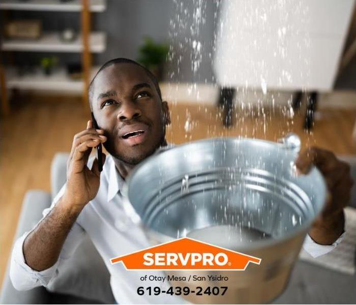 A person holds a bucket to catch water while calling for help.