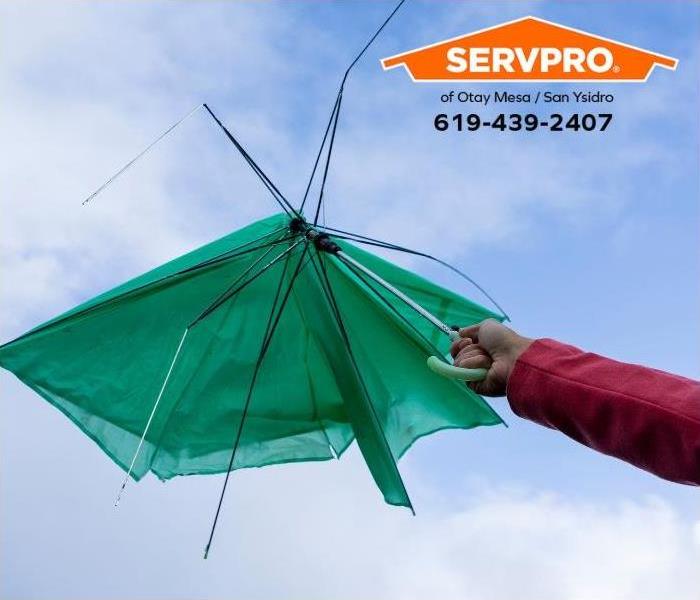 An umbrella breaks during a strong wind gust.