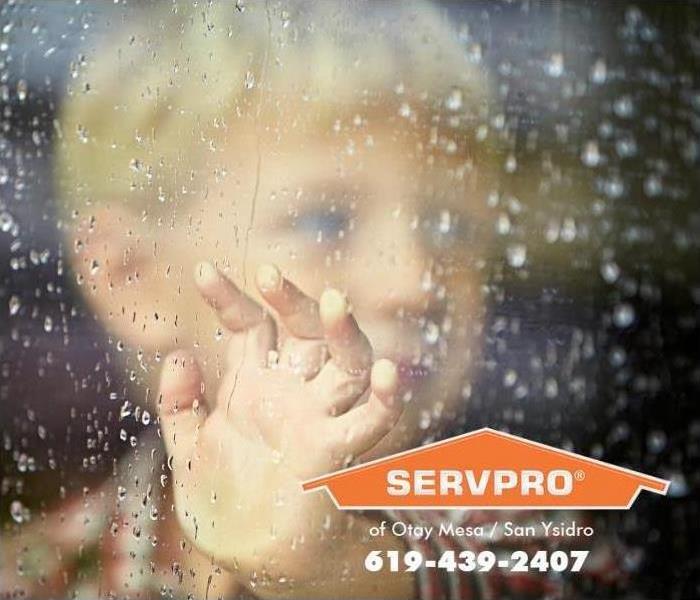 Young boy looking out of rainy window