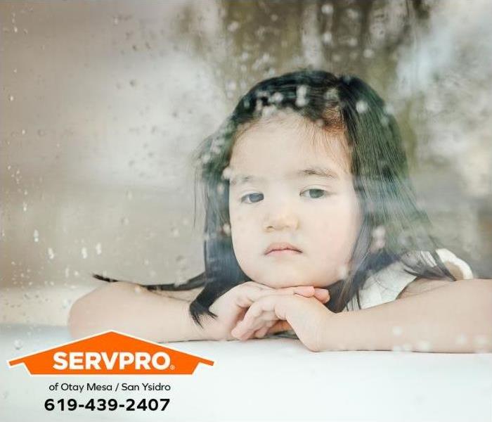 A child watches the rain through a window.