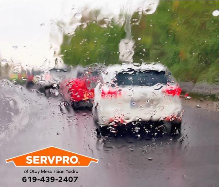 Cars are driving on a highway during a rainstorm.