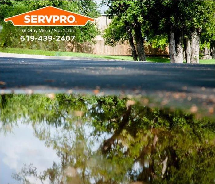 A large water puddle sits on a flooded neighborhood street.